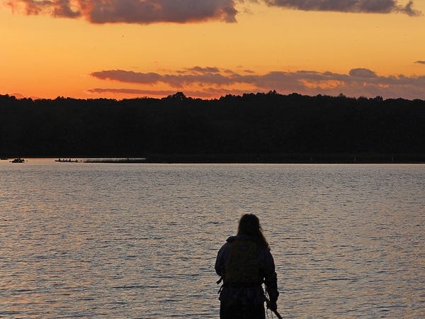 A stand-up paddleboarder in the middle of Nimisila Reservoir at sunset.