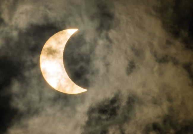 A partial eclipse in a foggy sky.