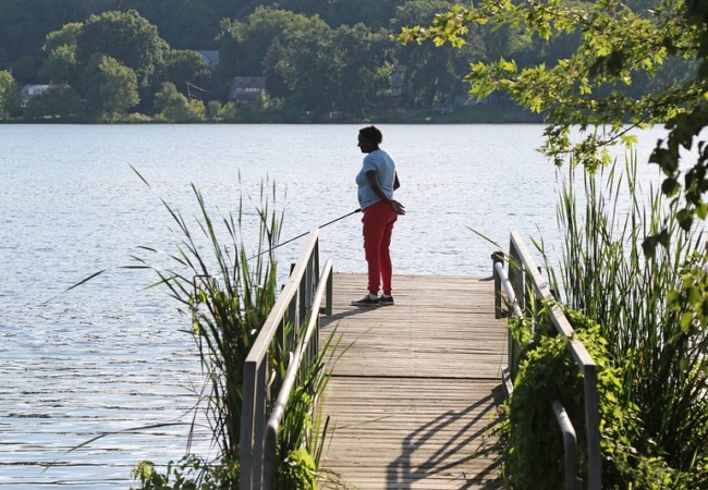 A woman stands fishing on a dock that extends into Summit Lake.