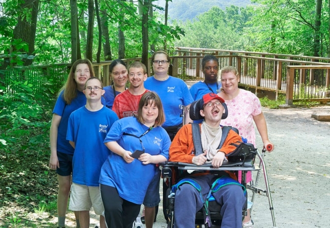 A group of UDS clients pose for the camera in front of the Cuyahoga River overlook on Overlook Trail in Cascade Valley Metro Park.