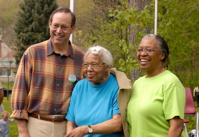 A man and two women smile toward a camera.