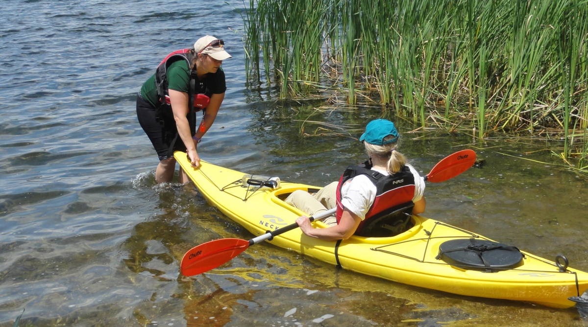 Woman helping another woman start her kayaking adventure