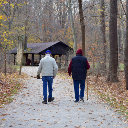 A man and woman walk along a crushed sandstone path toward a wooden shelter.