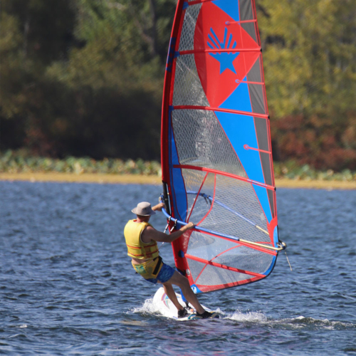 A man windsurfing across a lake.