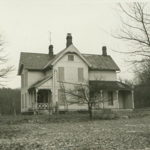 A black and white photo of an old farmhouse.