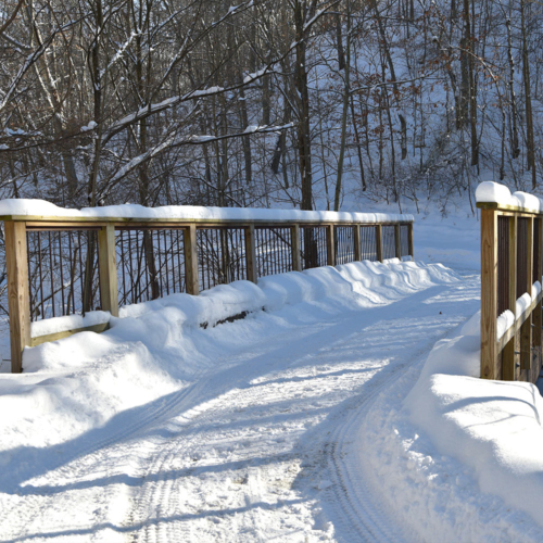 A snow-covered wooden trail bridge.